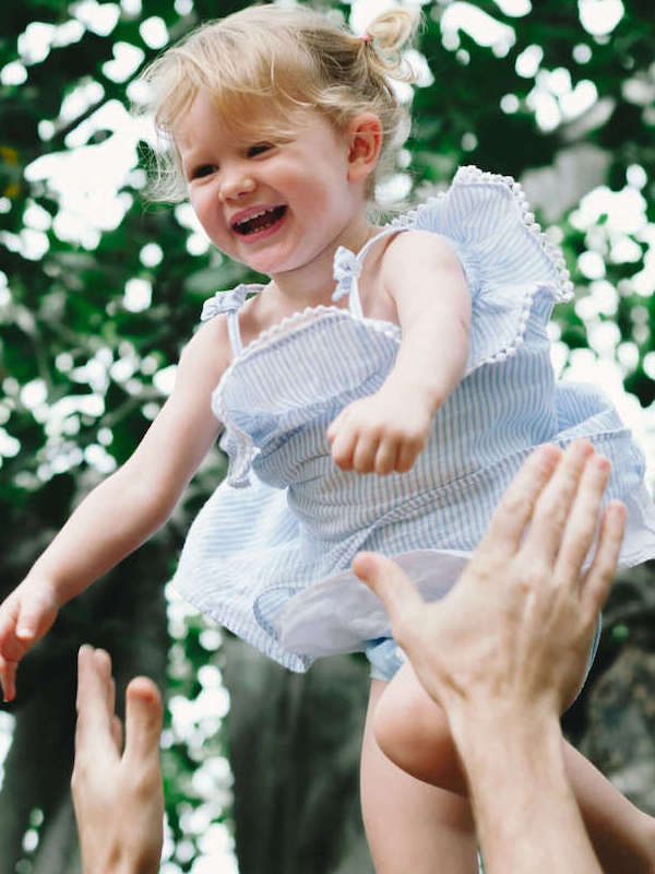 Toddler being lifted into the air by a parent outdoors